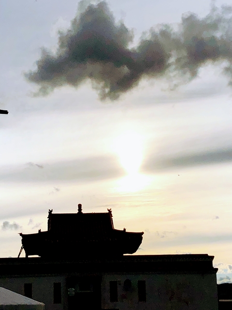 Overexposed image of the sun setting with a silhouetted structure.