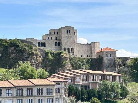       Fortress with stone walls and towers under a blue sky.
  