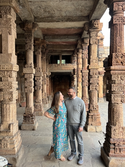 Couple standing among intricately carved stone pillars.