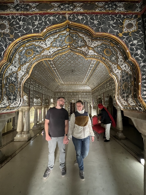 Two people in an ornate interior space with carved archways.