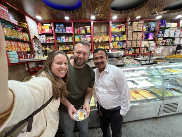 People in a sweet shop holding a dessert.