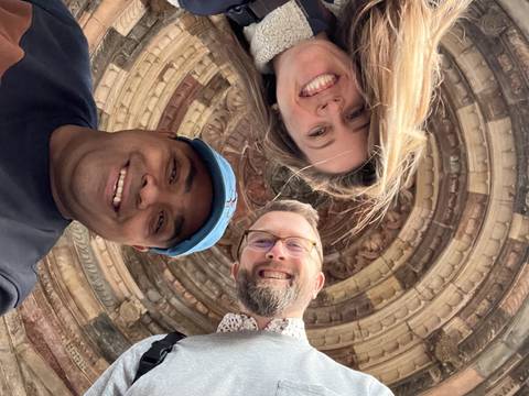 Selfie with three people under architectural detail.