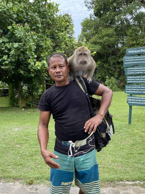       Man with a monkey on his shoulder posing for the camera.
  