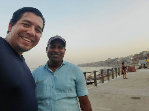 Two people smiling with a river and buildings in the background.