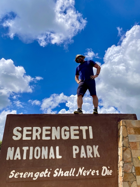       Person standing on a sign with 'Serengeti' written on it.
  