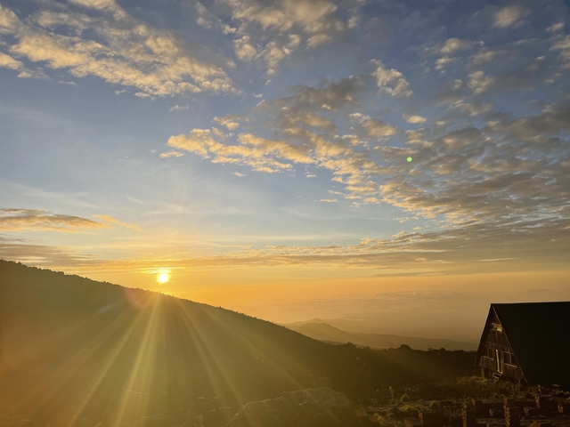 Sunrise over a mountain landscape with a building.