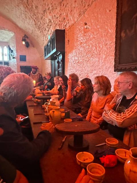 Group of people having a meal at a long table in a dimly lit room.