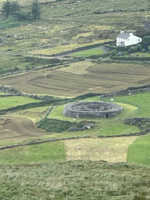 Aerial view of a stone ring fort in a grassy landscape.
