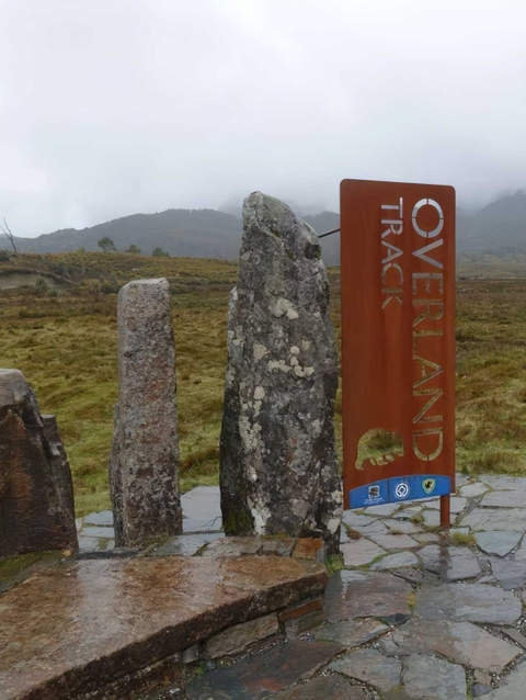 Entrance sign to Overland Track with mountainous background.