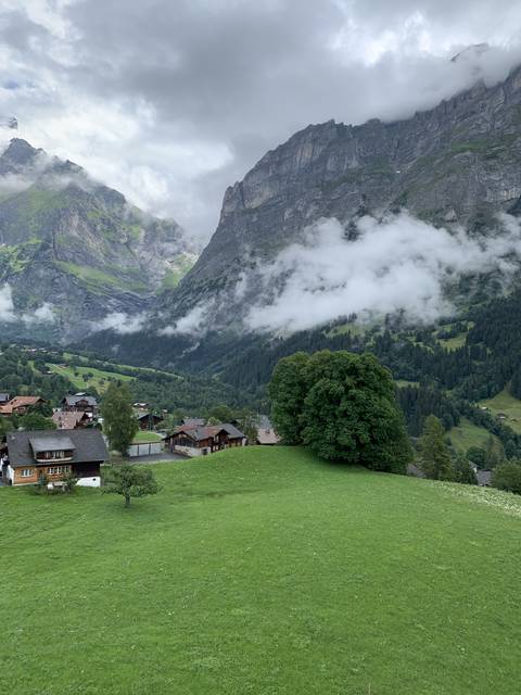      A lush green valley surrounded by mountains and clouds.
  