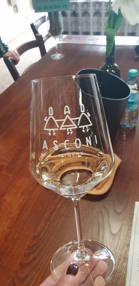       Close-up of a wine glass labeled Asconi Winery on a wooden table.
  