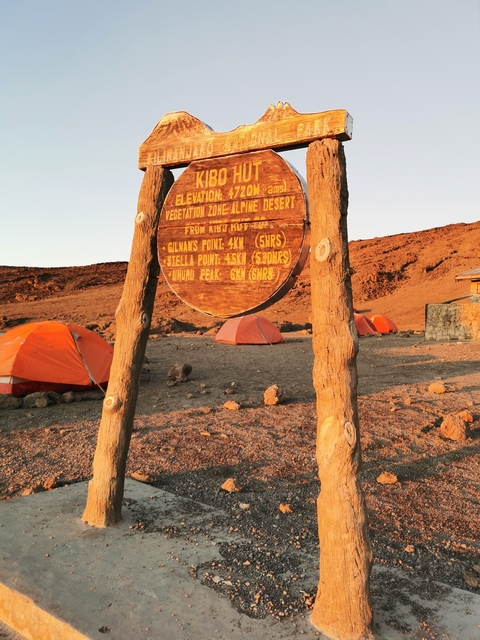       A campsite with tents and a wooden sign.
  