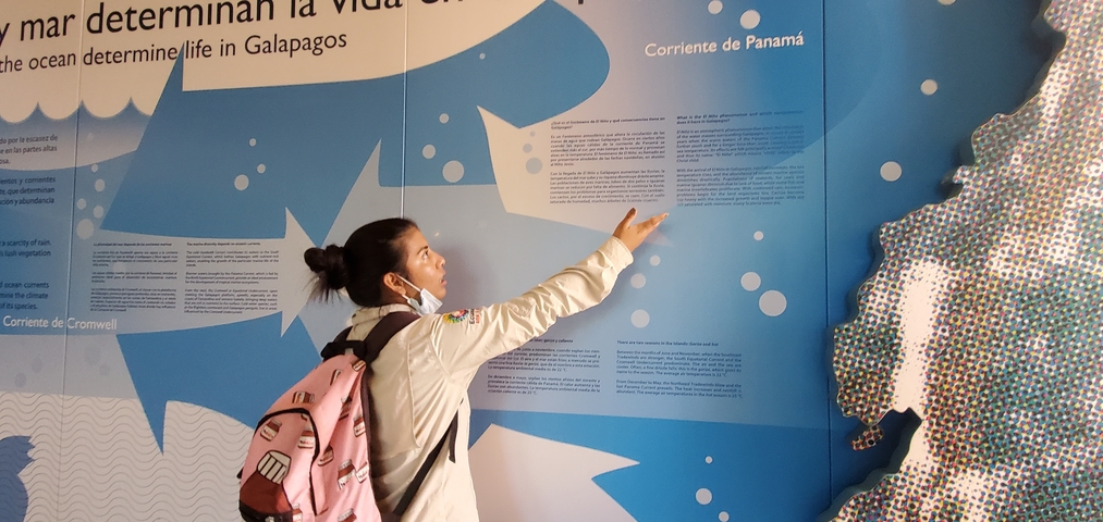 Person pointing at an informational display about life in Galapagos.