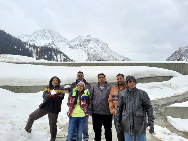 Group of people posing in the snow with mountains in the background.