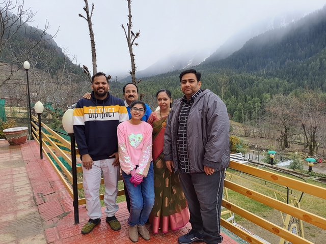 Family posing on a veranda with scenic mountain view.