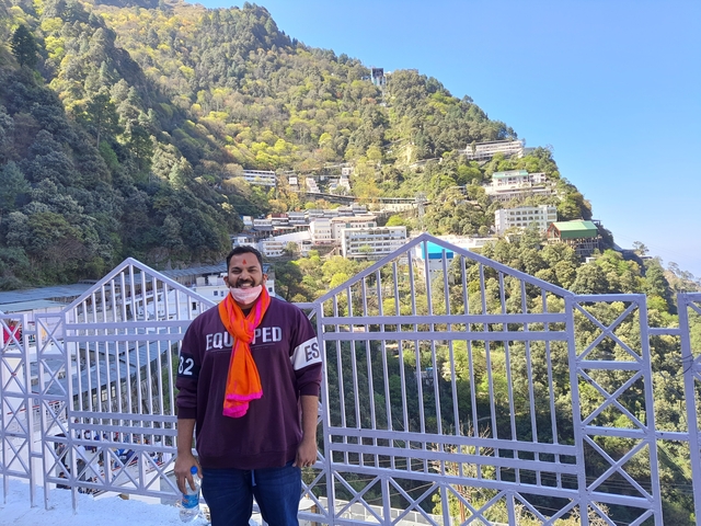 Person posing with colorful landscape and houses in the background.