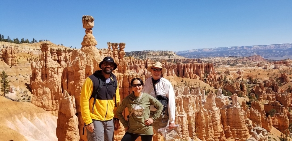 Three people posing in front of unique rock formations.
