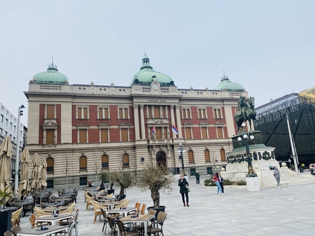       A historic building with domes and a statue in the foreground.
  