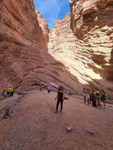 Group of people inside a narrow canyon with high walls.