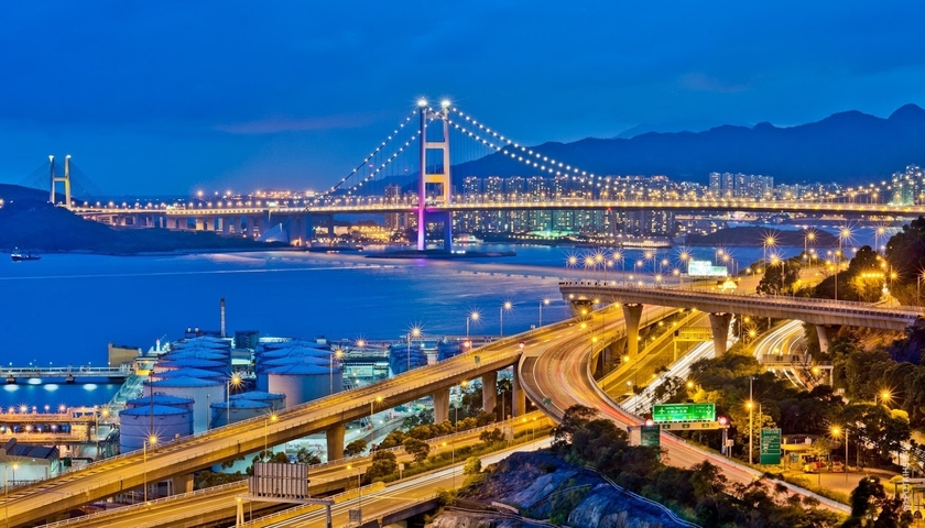 Cityscape at night with illuminated bridge and highways.