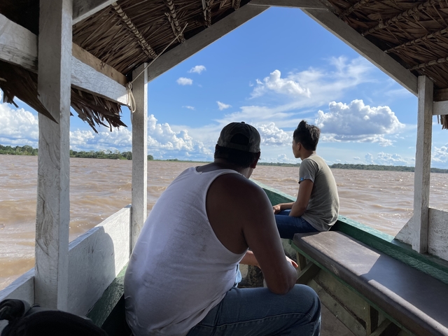 Two people sitting in a boat on a river.