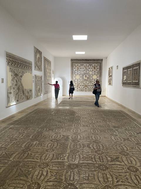 A museum interior with intricate tilework and people exploring.
