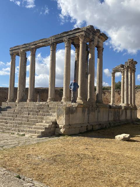       Ruins of an ancient structure with a person standing on the steps.
  