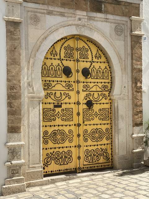 Ornate yellow and black patterned door within a stone building.
