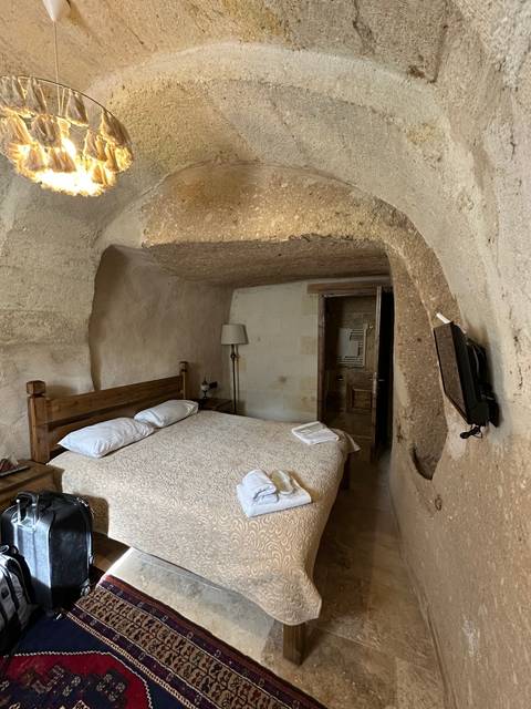       Interior of a cave hotel room with a made bed and stone walls.
  