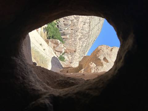 View through a cave opening to rock formations.