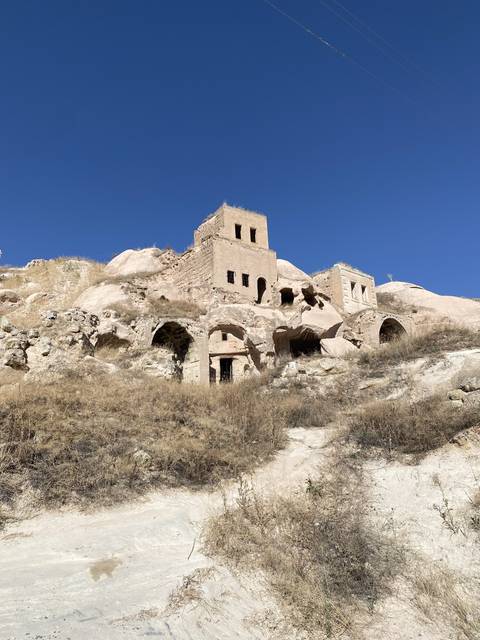 Rocky structures and cave dwellings with a blue sky.