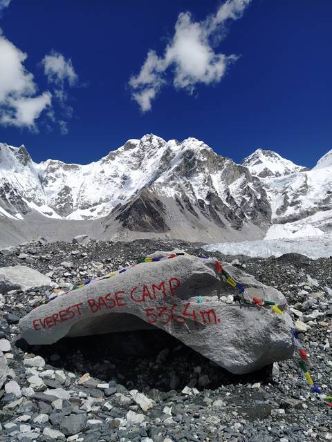 Everest Base Camp marker with snowy mountains in the background.