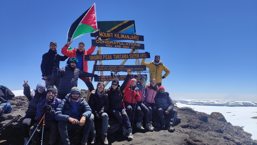       Group of hikers posing at Uhuru Peak of Mount Kilimanjaro.
  