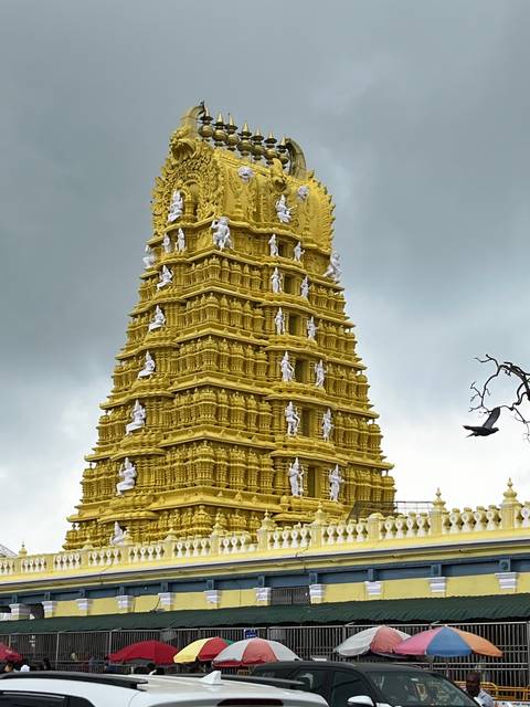 Tall ornate temple tower with intricate carvings against a cloudy sky.