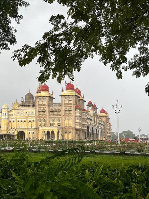 Majestic palace with red domes set amidst lush greenery.