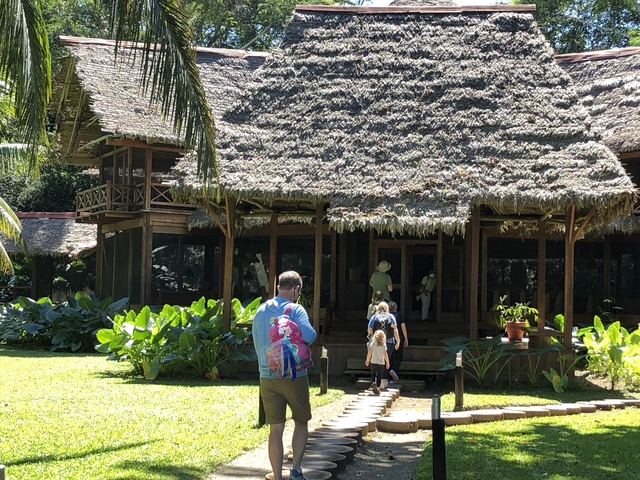 Family walking toward a large thatched-roof building
