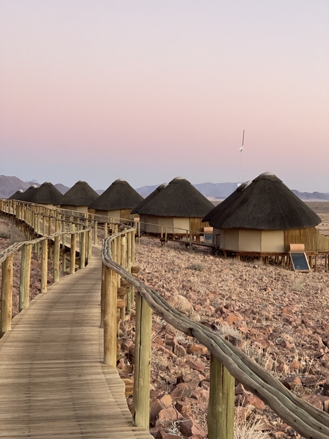       Row of thatched-roof huts at sunset.
  