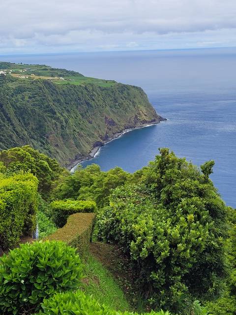 Scenic coastal landscape with green hills and ocean.