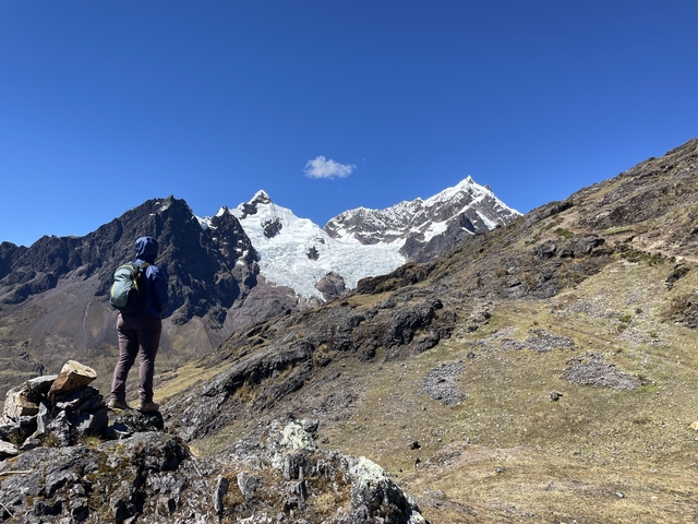 Person hiking with mountains and snow in the background.