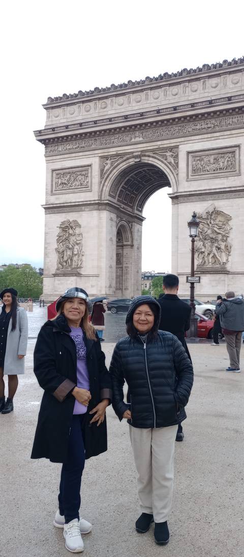 Two women standing before the Arc de Triomphe.