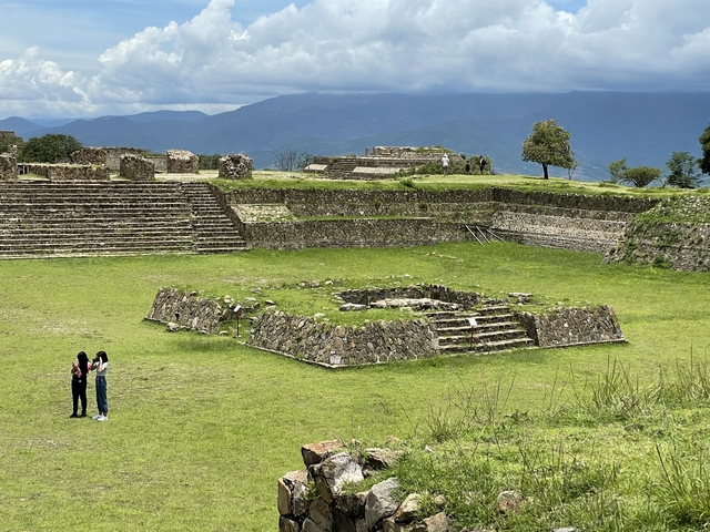       Two people exploring ancient Monte Alban ruins
  