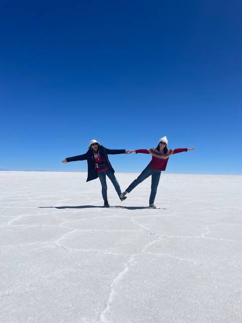 Two people posing on a salt flat.