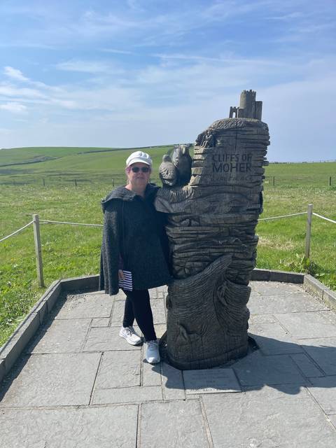Person posing next to a Cliffs of Moher sculpture.