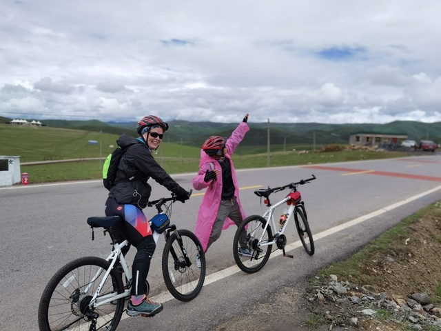 Two people on bicycles in a scenic rural landscape.