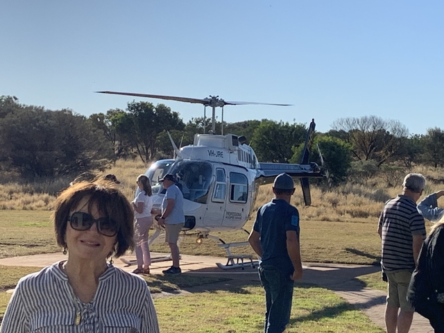       People standing near a helicopter on a field.
  