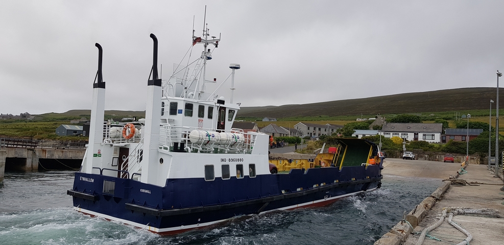       Ferry boat at a dock in a hilly coastal town.
  
