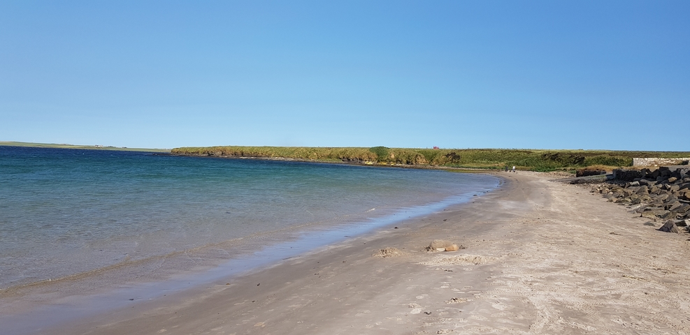       Empty beach with clear skies and a distant coastline.
  
