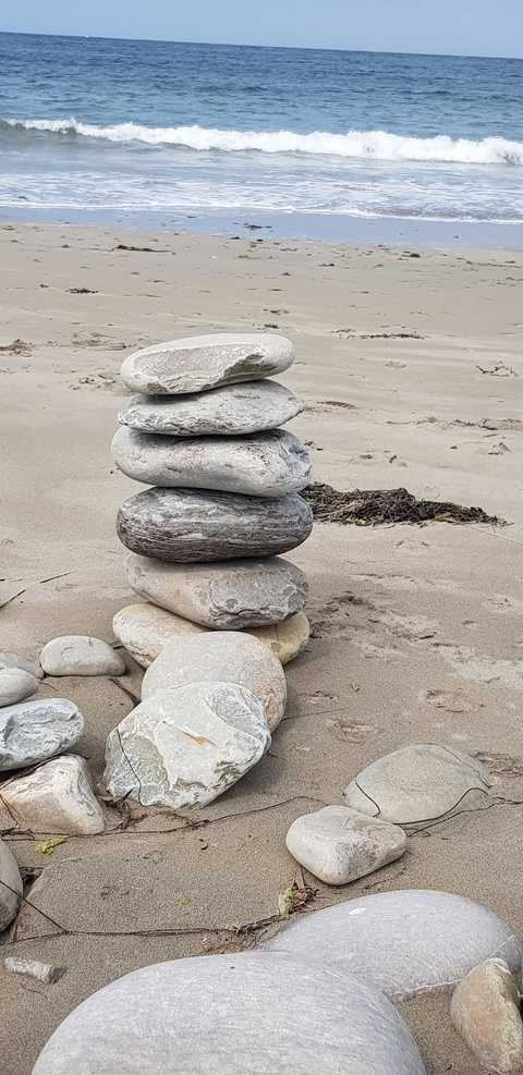       Stacked stones on a sandy beach.
  