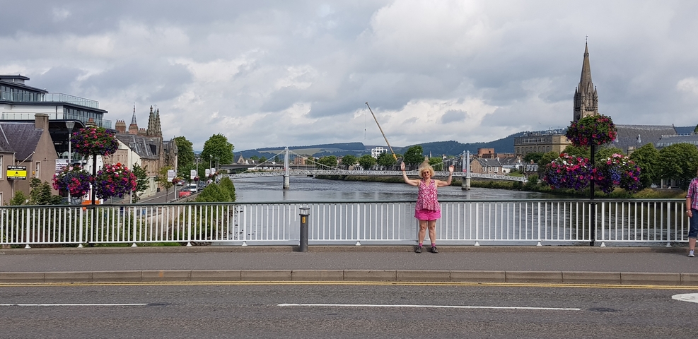      Person standing at a riverside with city view.
  
