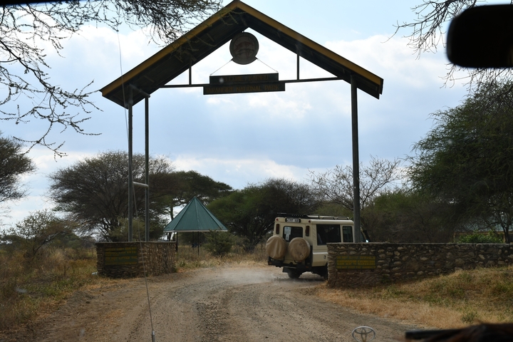       Entrance gate to a national park with a vehicle departing.
  